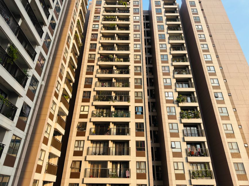 High-rise apartment buildings with balconies in an urban setting under a clear blue sky, emphasizing modern architecture.