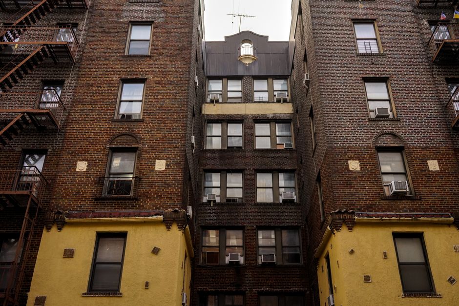 Low-angle view of urban brick apartment buildings with fire escapes, embodying classic city architecture.